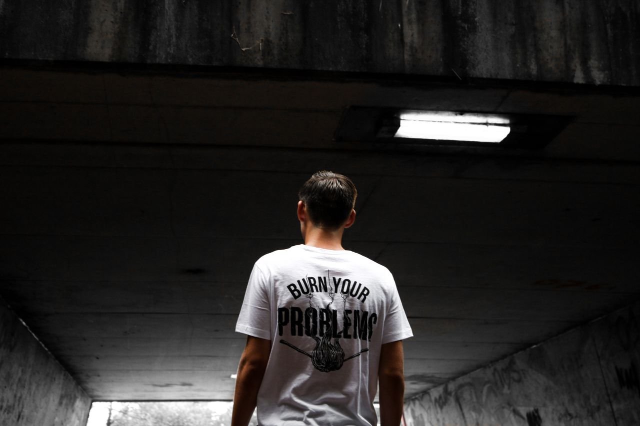 A man stands in an urban tunnel wearing a t-shirt with a bold statement.